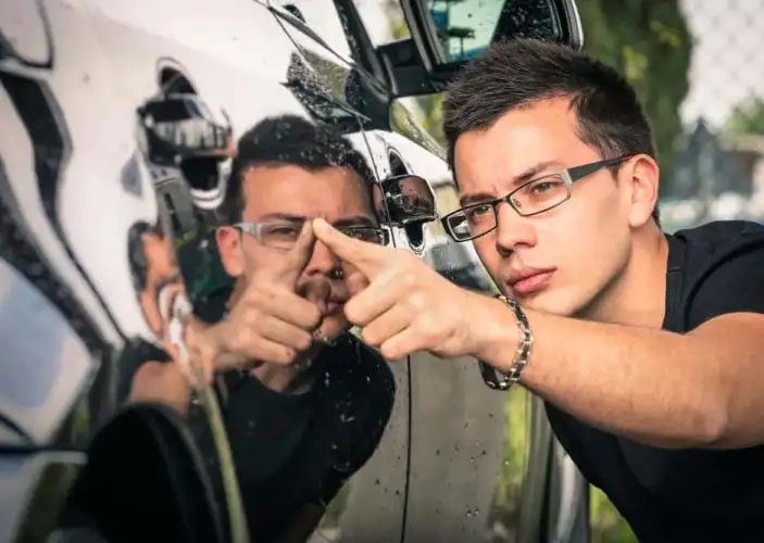 Klient ogląda zarysowany lakier na aucie